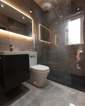 Bathroom with grey marble-effect tiles, dark vanity and illuminated mirror