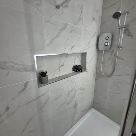 Shower enclosure with white marble-effect tiles and a recessed niche
