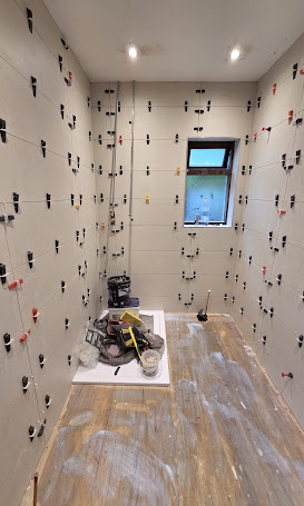 Bathroom wall tiling in progress around a shower tray