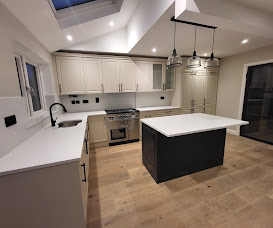 Kitchen with off-white shaker cabinets, dark island and oak flooring