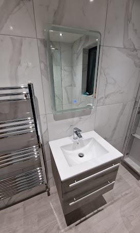 Bathroom with white marble-effect tiles, grey vanity and heated towel rail